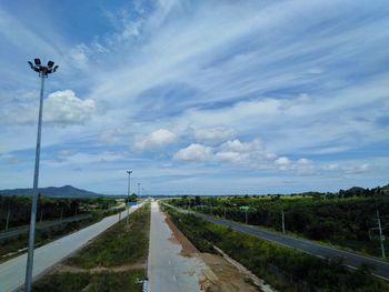 Street amidst field against sky