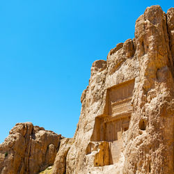 Low angle view of rock formation against clear blue sky