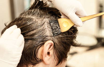 Cropped hands of barber coloring woman hair