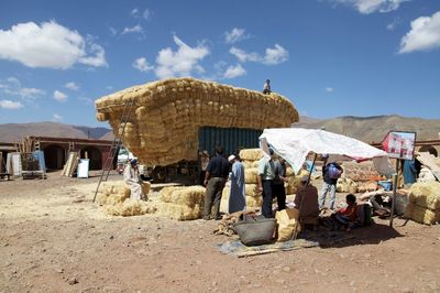 People by over-burdened truck with straw bundles at market