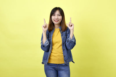 Portrait of smiling woman standing against yellow background