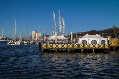 Boats in river at flensburg against clear blue sky on sunny day