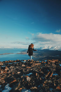 Woman standing on rocks against sky