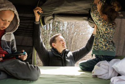 Father setting up roof top tent with his kids for social distance