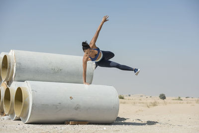 Young woman on sand at beach against clear sky