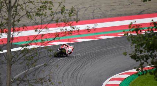 Rear view of man riding motorcycle on motor racing track