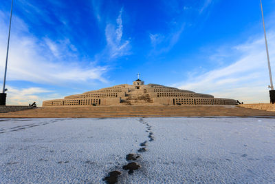 Built structure on snow covered land against blue sky