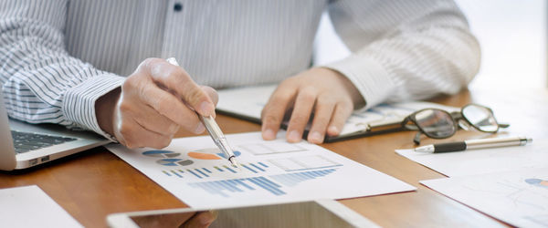 Midsection of man holding paper with text on table