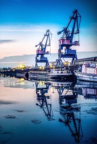 Cranes at commercial dock against sky