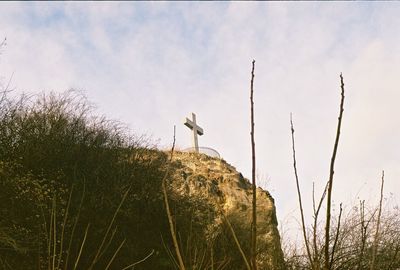 Low angle view of cross on rock formation against sky