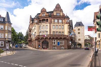 Cars on road by buildings against sky in city