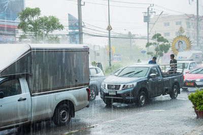 Cars on street by buildings in city during rainy season