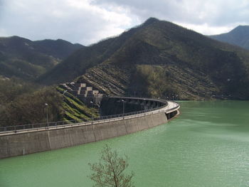 Scenic view of river and mountains against cloudy sky