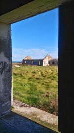 Buildings on field against blue sky