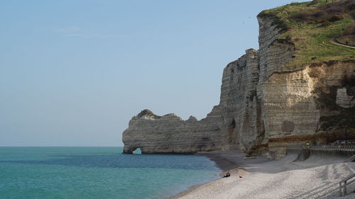 Scenic view of cliff by sea against clear sky