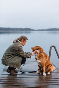 Young woman with dog on pier by lake