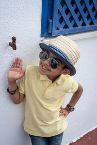 Boy wearing hat standing by wall