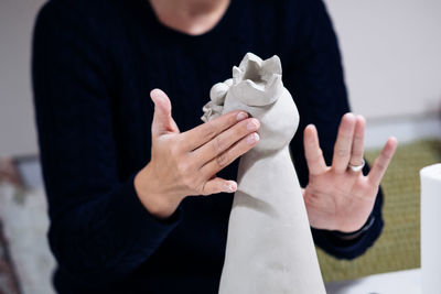 Midsection of artist sculpting bird at workshop