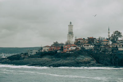 Buildings by sea against sky in city