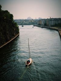 Sailboat sailing on river in city against clear sky