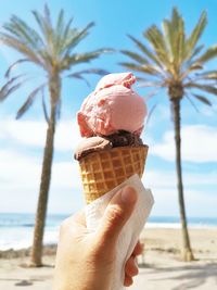 Close-up of hand holding ice cream cone on beach