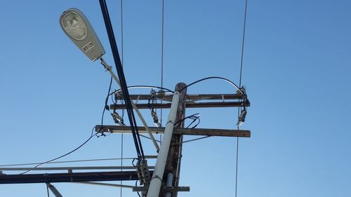 Low angle view of electricity pole against blue sky