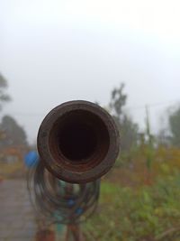 Close-up of rusty metal on field against sky