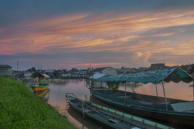 Boats moored in sea against sky during sunset