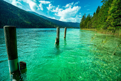 Wooden posts in lake against sky