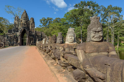 Statues by road against sky