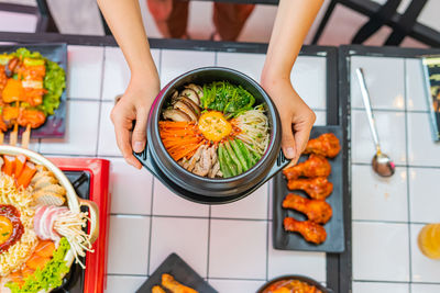 High angle view of woman holding food on table