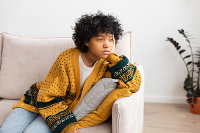 Young woman sitting on sofa at home