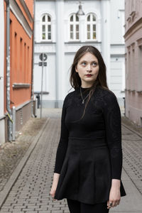 Portrait of young woman standing on street in city