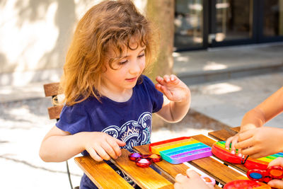 Cute girl holding toy while sitting on table