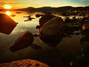 Rocks on beach against sky during sunset