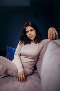 Portrait of young woman sitting on sofa at home