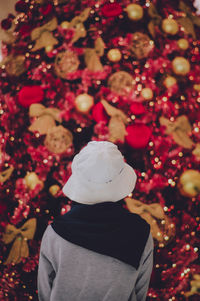 Rear view of woman standing by christmas tree