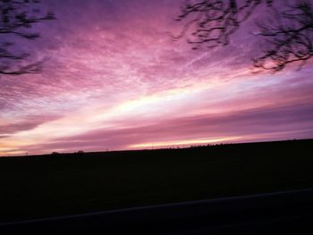 Silhouette landscape against dramatic sky during sunset