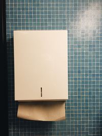 Towel dispenser on tiled wall in bathroom