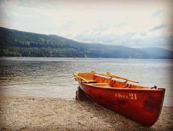 Boat moored on lake against sky