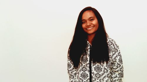 Portrait of young woman standing against white background