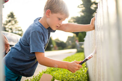 Side view boy painting fence