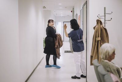 Rear view of female doctor waving at patient leaving medical clinic