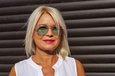 Portrait of blonde in sunglasses on background of brown blinds shutters garage house