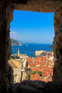 Buildings by sea against blue sky