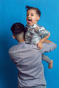 Dad in a shirt with his son standing in the studio on a blue background