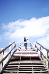 Low angle view of woman standing against cloudy sky