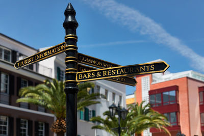 Low angle view of sign by building against sky