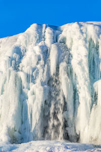 Panoramic view of frozen lake against clear blue sky