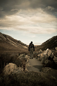 Man standing on rock against sky